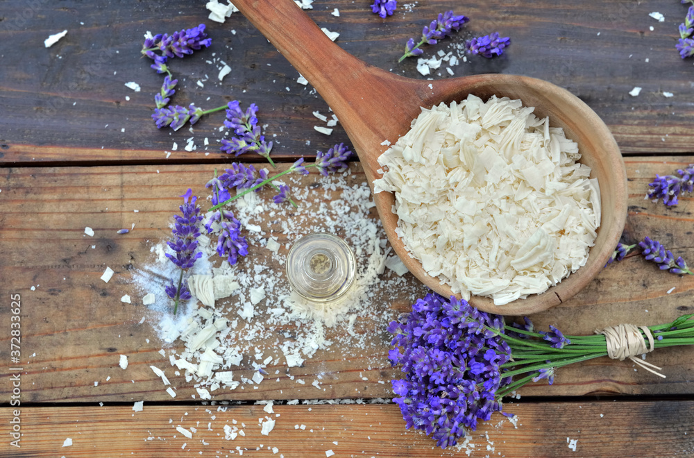 spoon full of flakes of soap with essential oil and bunch of lavender flowers spoon full of flakes of soap with essential oil and bunch of lavender flowers