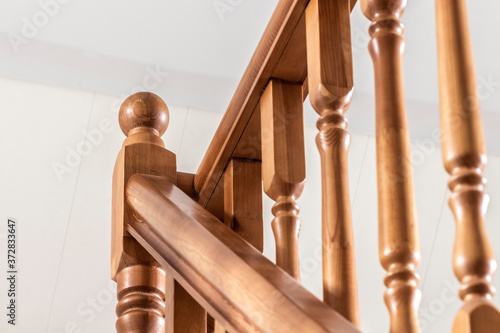 Element of a wooden interior staircase. Wooden baluster close-up.