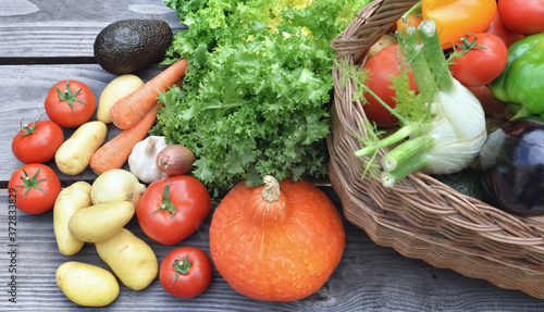 various  and colorful vegetables on a wooden table with a wicker basket