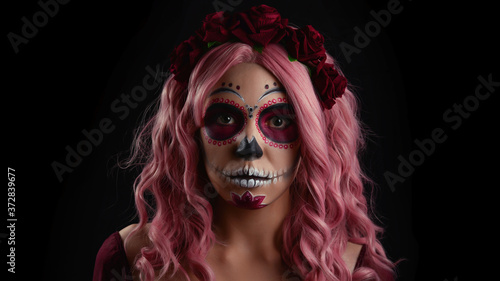 Woman with sugar skull makeup and pink hair isolated on black background. Day of the dead. Halloween.