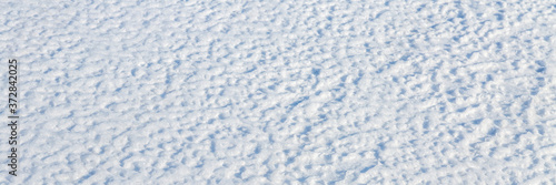 Natural snow texture. The surface of the snow crust. Snowy ground. Winter background with snow patterns. Perfect for Christmas and New Year design. Closeup top view.