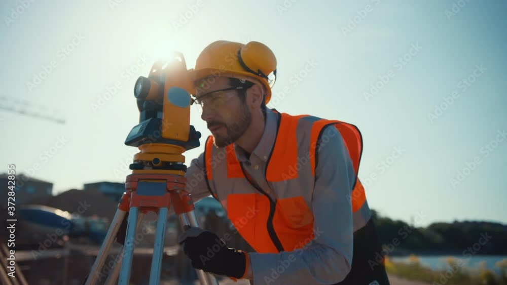 Construction Worker Using Theodolite Surveying Optical Instrument for Measuring Angles in