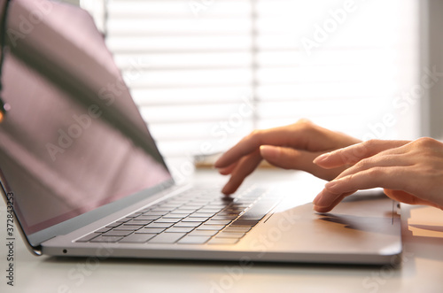 Woman working with modern laptop at white table, closeup