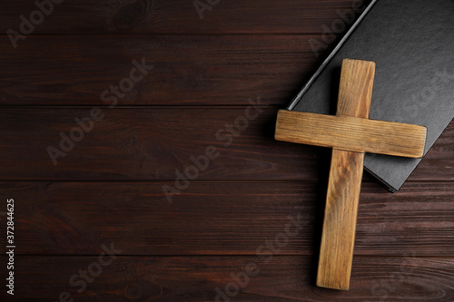 Christian cross and Bible on wooden background, top view with space for text. Religion concept