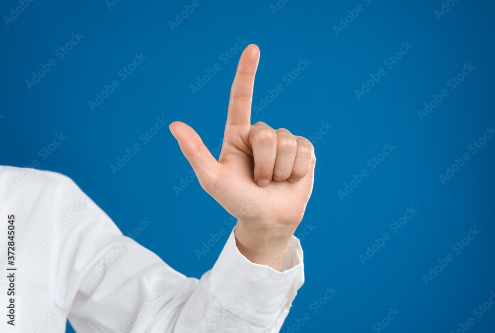 Young woman touching something against blue background, closeup view Young woman touching something against blue background, closeup view