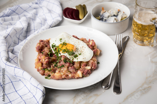 Norddeutscher Hamburger Labskaus mit Rindfleisch Corned Beef, Rote Beete, Kartoffeln, Saure Gurken, Spiegelei, Rollmops und Bier auf Marmor photo