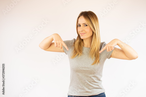 Young woman in grey shirt pointing something with fingers down