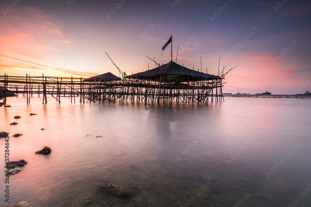 traditional bamboo hut in the middle of the sea at sunset