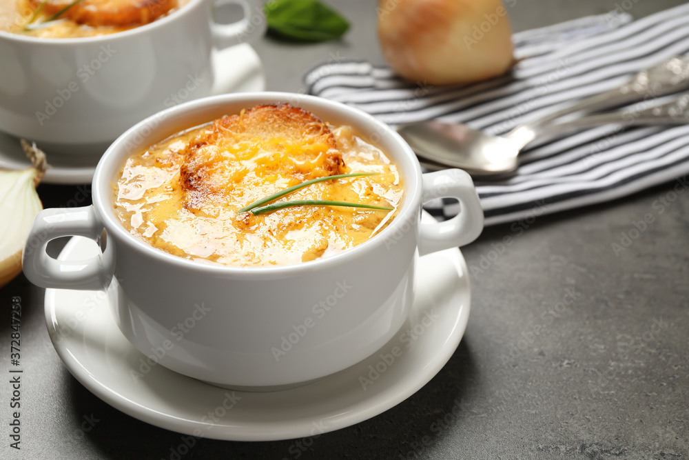 Tasty homemade french onion soup served on grey table Tasty homemade french onion soup served on grey table