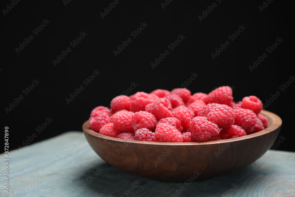 Delicious fresh ripe raspberries in plate on blue wooden table Delicious fresh ripe raspberries in plate on blue wooden table