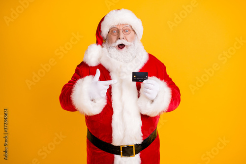 Grey white beard hair santa claus big belly point finger credit card impressed x-mas eve noel magic miracle christmas discount party wear cap white gloves isolated bright shine color background