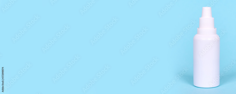 Nasal spray, drops in white bottle, isolated on blue background, copy space template, banner. Nasal spray, drops in white bottle, isolated on blue background, copy space template, banner.