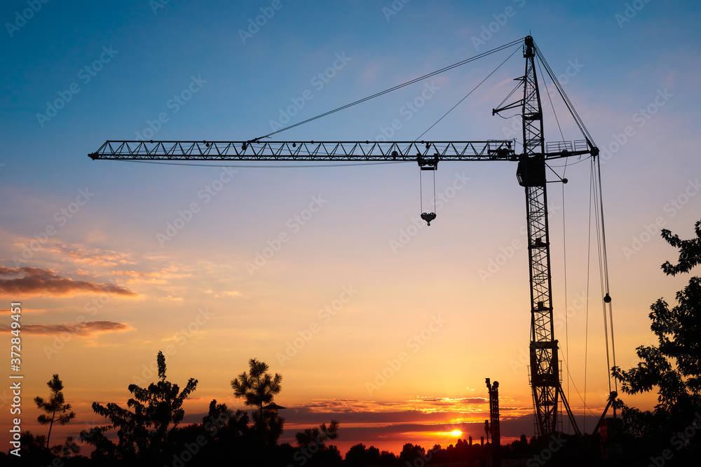 silhouette tower construction crane on sunset background, copy space