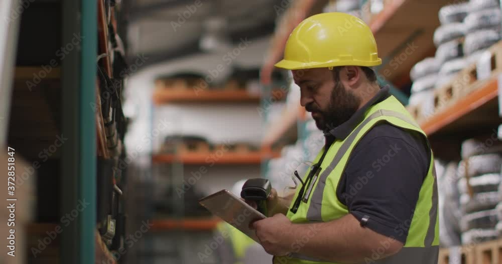 Caucasian male factory worker at a factory wearing a hard hat and high vis vest, checking stock Caucasian male factory worker at a factory wearing a hard hat and high vis vest, checking stock