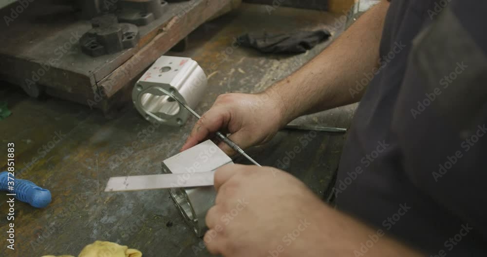 Caucasian male hands factory worker at a factory sitting at a workbench and working on a metal Caucasian male hands factory worker at a factory sitting at a workbench and working on a metal