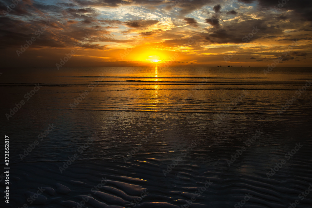 Fototapeta premium The golden hour morning sea when the sun just rises and the sea still darkens on a calm day. The sun reflects the water like gold.