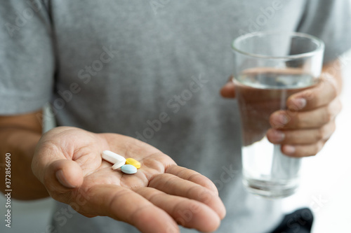 Taking medicine pills concept. Man holds in hands the medicine pills and a glass of water. Health care or treatment for viral infections