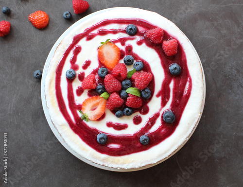 Top view of whole cheesecake with berries and coulis on top