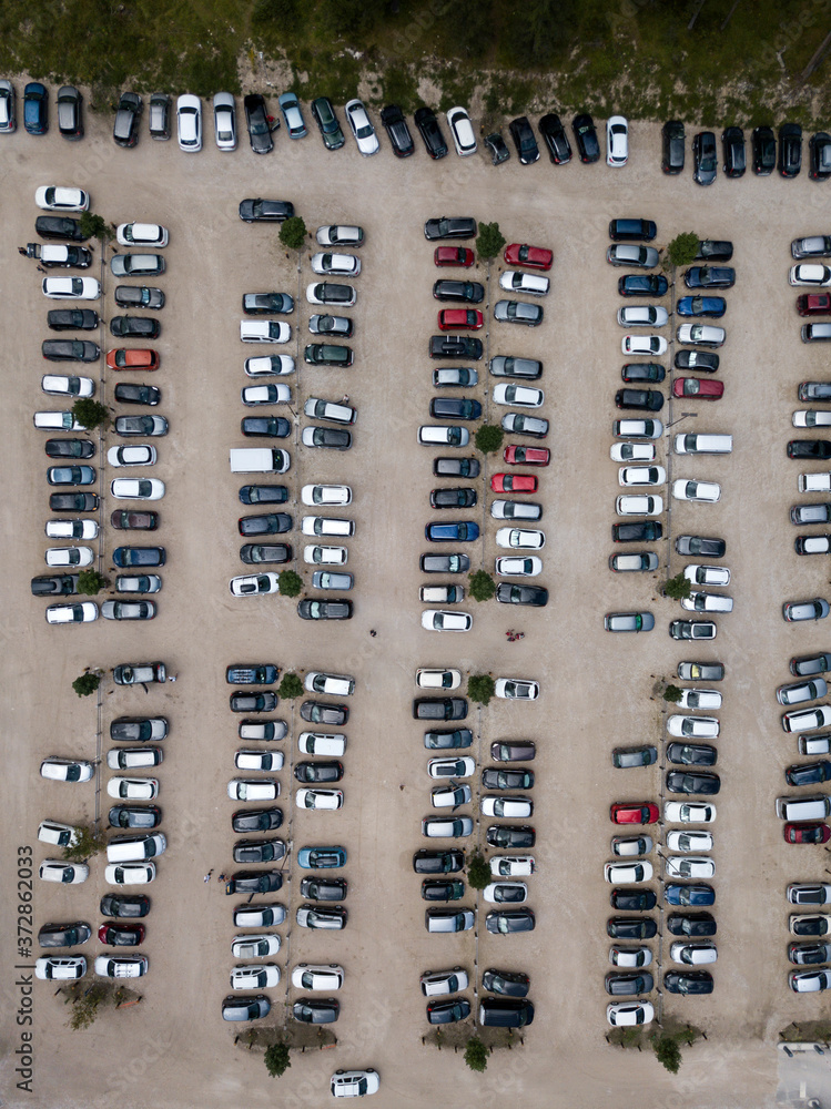 Aerial top down view of parking, many cars standing in row. Parked automobiles, trees. Parking on sand.