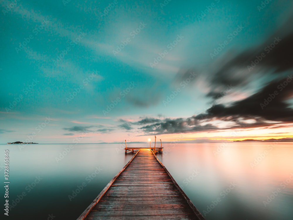 Fototapeta premium Wooden jetty at sunset over the ocean, long exposure