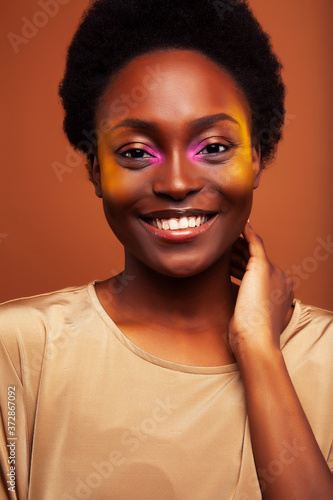 pretty young african american woman with curly hair posing cheerful gesturing on brown background, lifestyle people concept © iordani
