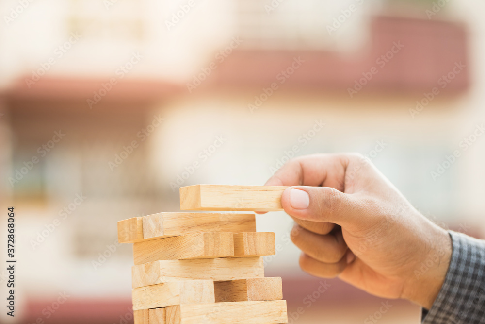 Close up male hand holding arranging or pick up the block wood game and stacking. Growth of Business financial investment and bankrupt concept. Close up male hand holding arranging or pick up the block wood game and stacking. Growth of Business financial investment and bankrupt concept.