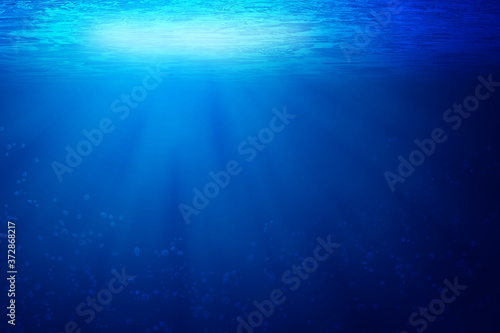 Abstract image of Tropical underwater dark blue deep ocean wide nature background with rays of sunlight.