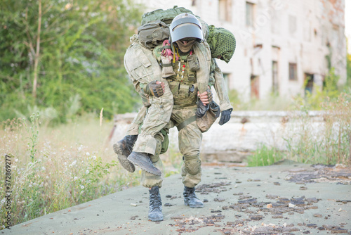 Military partner carries his wounded partner from shelling