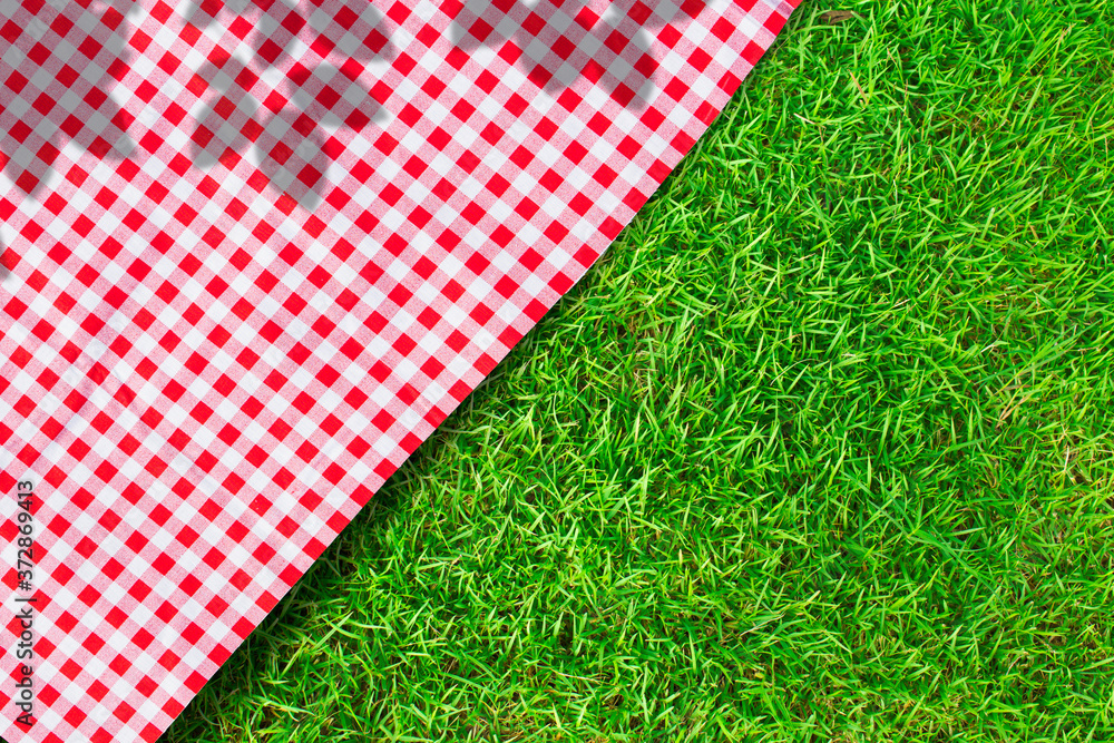 © Angkana - Red checkered table cloth on green turf or grass from top view. © Angkana - Red checkered table cloth on green turf or grass from top view.