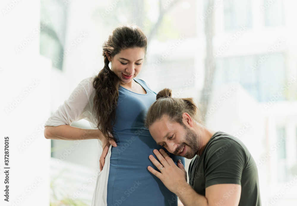 Beard man take care his pregnant wife and listen to the baby. Beard man take care his pregnant wife and listen to the baby.