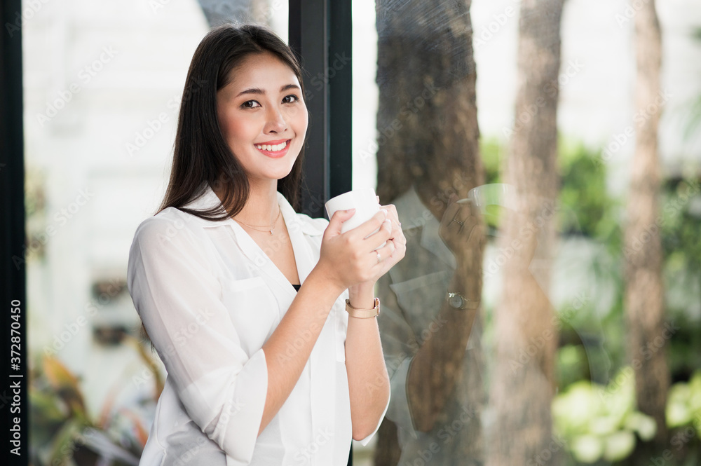 Beautiful asian woman drinking coffee at home in the morning. Smiling charming happy young female stay at home. Beautiful asian woman drinking coffee at home in the morning. Smiling charming happy young female stay at home.