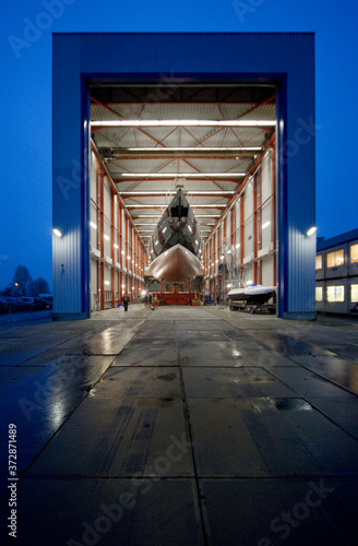 Transport of a super sailing yacht at the shipyard. Boat casco. Shipbuiling industry. At night. Shed.