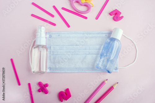 Education or back to school concept. Set of pink school supplies, medical face mask and antiseptic sanitizer gel. New normal during coronavirus pandemic. Virus protection, keep distance. Copy space