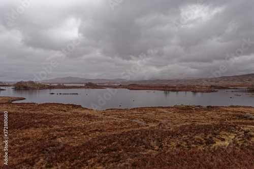 A bleak Loch Ba on Rannoch Moor on a wet day in April, with small Islands and large Boulders scattered across the Loch waters.