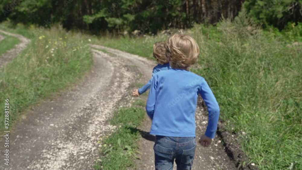 Children run along a rural road. Summer, nature, family vacation. Children run along a rural road. Summer, nature, family vacation.