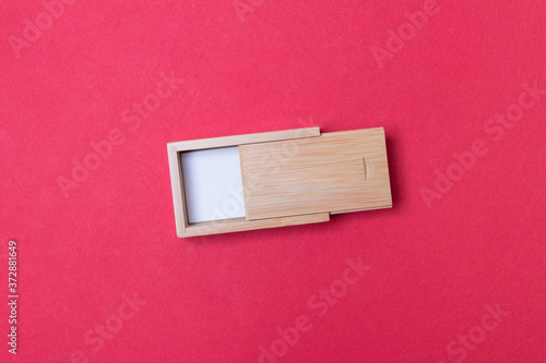 lightly open wooden box with place for you logo on red colored paper background