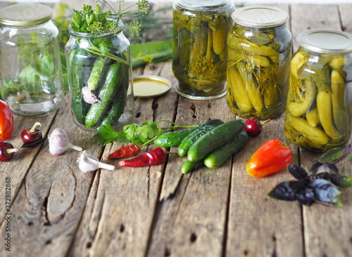 The process of preserving cucumbers in glass jars under lids for storage for the winter.Jars of cucumbers, ingredients for pickling on a wooden ancient natural table.