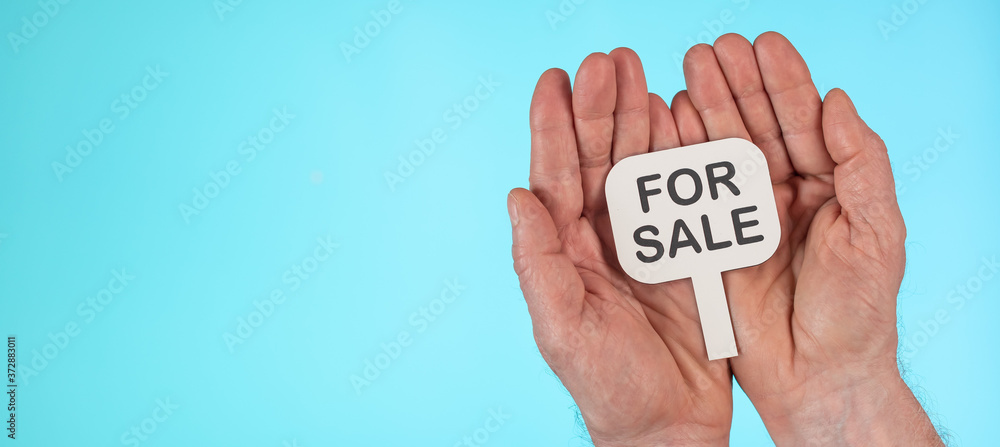 Hands holding a for sale sign Hands holding a for sale sign