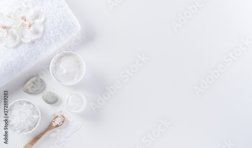 Cosmetic bottle containers, skin cream with flowers. Natural beauty and spa concept, Top view on white table background.