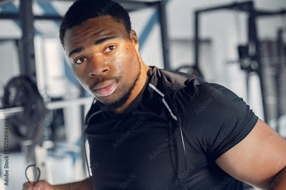 Sports man in the gym. A black man performs exercises. Guy in a black t-shirt Sports man in the gym. A black man performs exercises. Guy in a black t-shirt