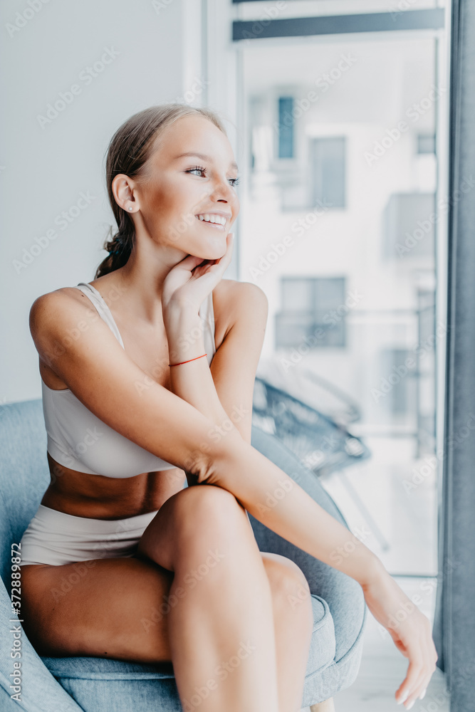 Young woman resting in the lace lingerie at home against big window. Young woman resting in the lace lingerie at home against big window.