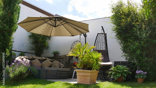 Gartenecke mit Loungegruppe unterm Sonnenschirm und umgeben von diversen Pflanzen © turtles2