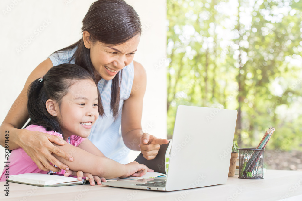 asia girl student online learning study online video call teacher. social distance during quarantine, self-isolation, online education concept, homeschool, cute girl with mother doing homework at home asia girl student online learning study online video call teacher. social distance during quarantine, self-isolation, online education concept, homeschool, cute girl with mother doing homework at home