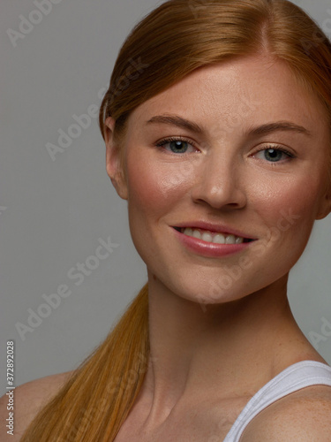 Freckles Woman portrait. Close-up. A beautiful gray-eyed girl with freckles is looking at the camera, on white background. Skin care. The beauty of red straight hair. Beautiful nude makeup. Pink lips