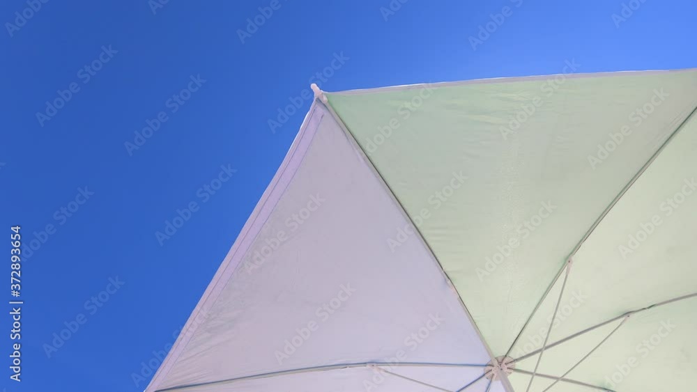 Low angle view of a Sun umbrella sunshade in a beach with blue sky in background Low angle view of a Sun umbrella sunshade in a beach with blue sky in background