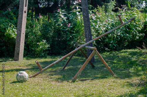 Abandoned playground on a sunny day. You can see a broken swing and a football without air.