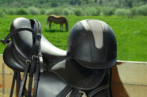 The bridle, the horse saddle and the riding helmet are in outdoors.