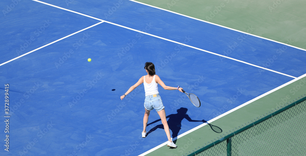 a girl hits the ball on a blue tennis court