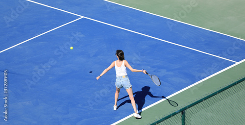 a girl hits the ball on a blue tennis court