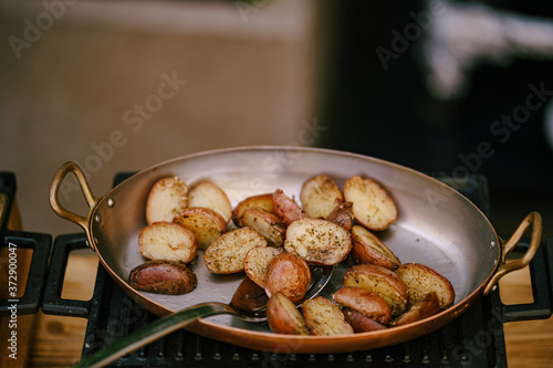 Close-up of fried potatoes in a frying pan on a cast iron stove on a gray background.